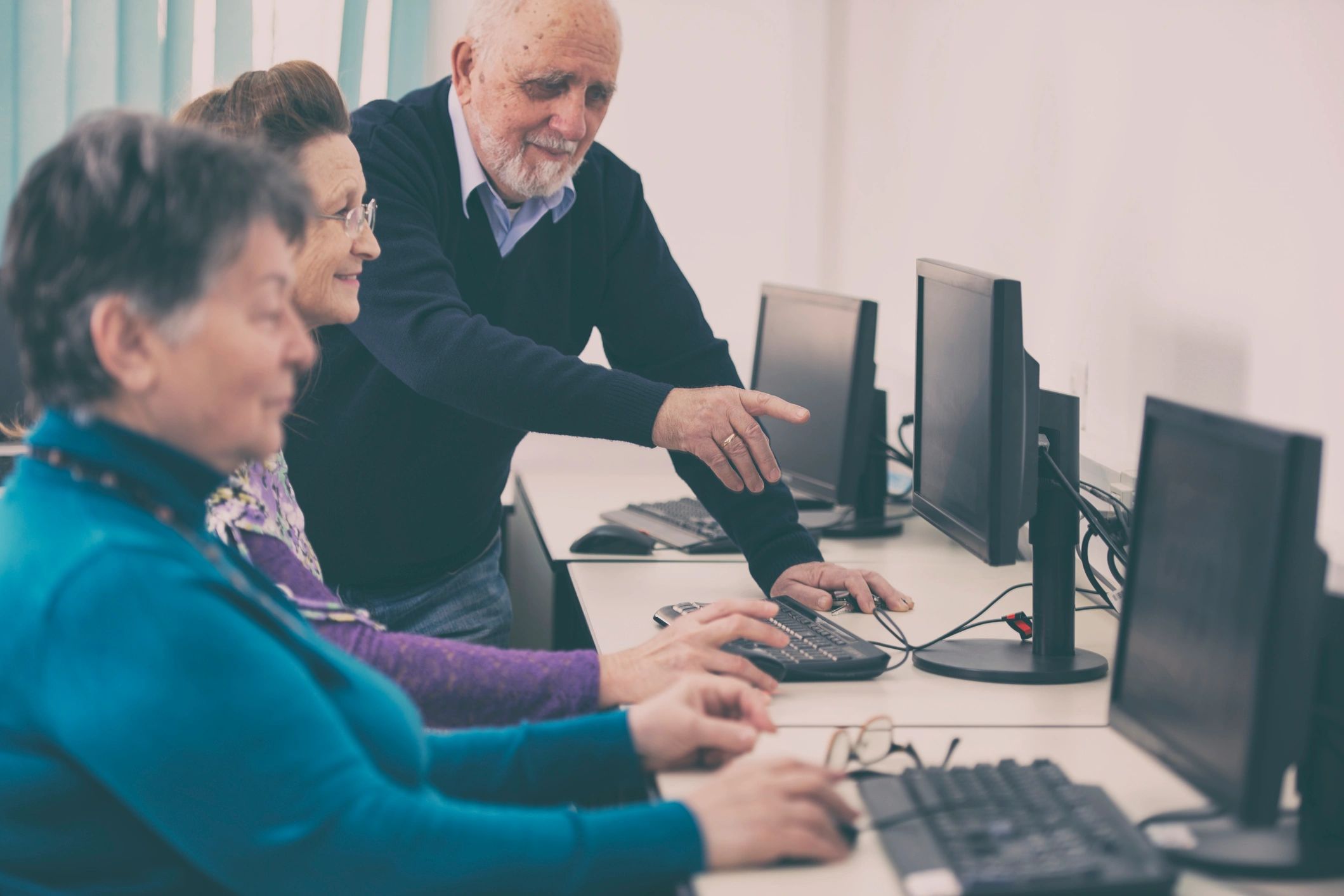 Instructor assisting seniors at computers during a training session