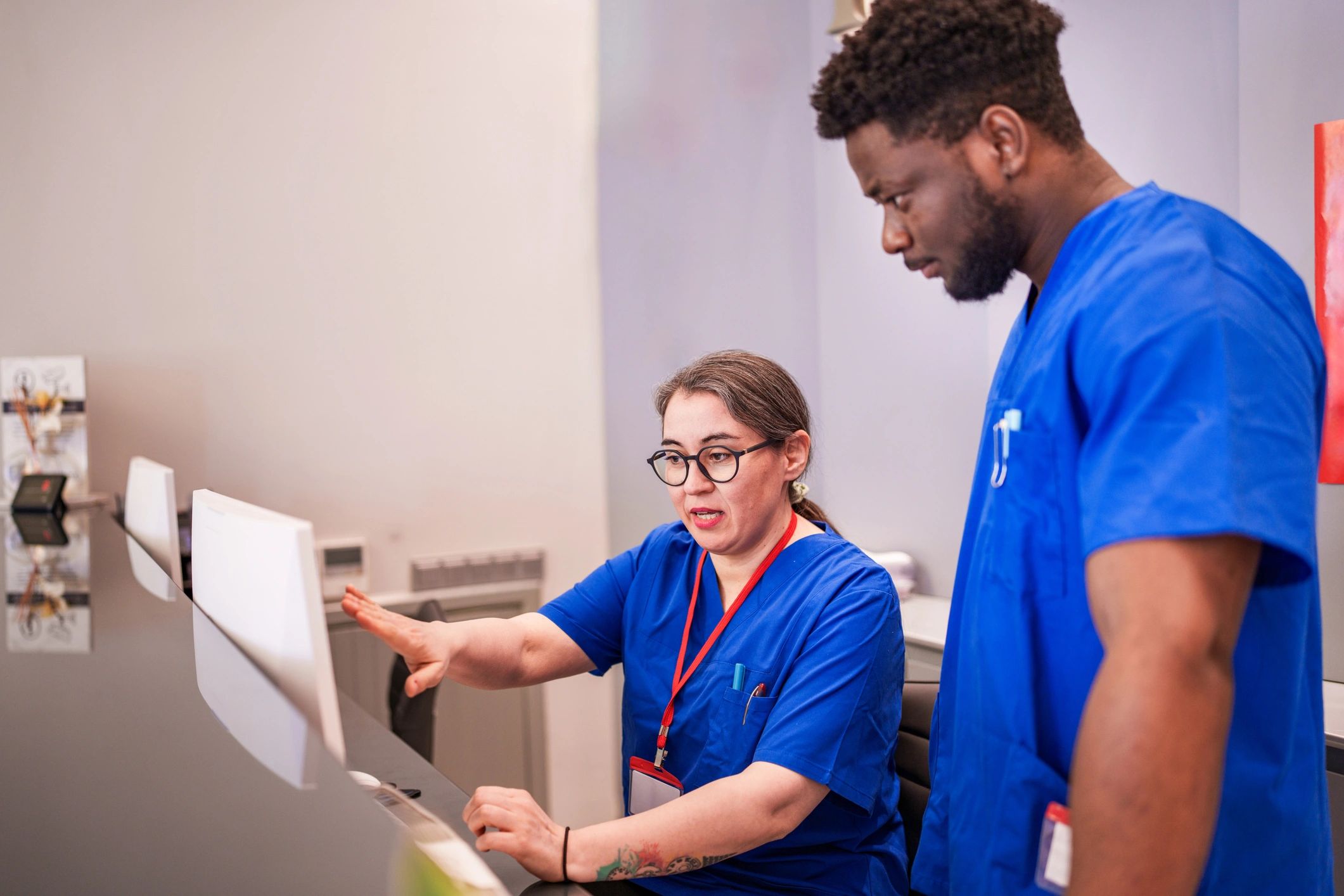 Healthcare staff collaborating at a computer in a clinical setting