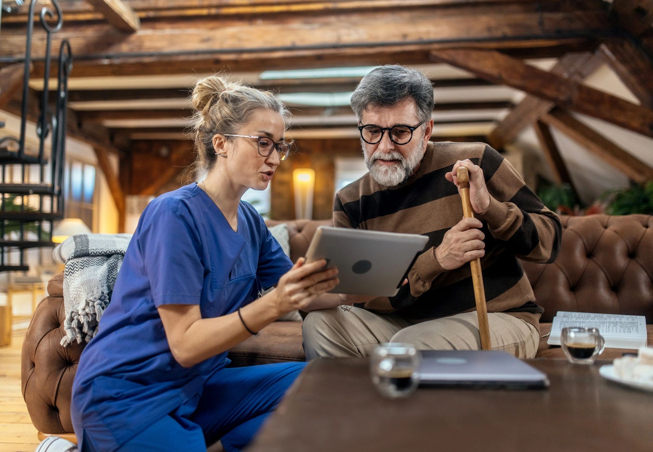 Nurse using a tablet while speaking with a resident in an assisted living facility
